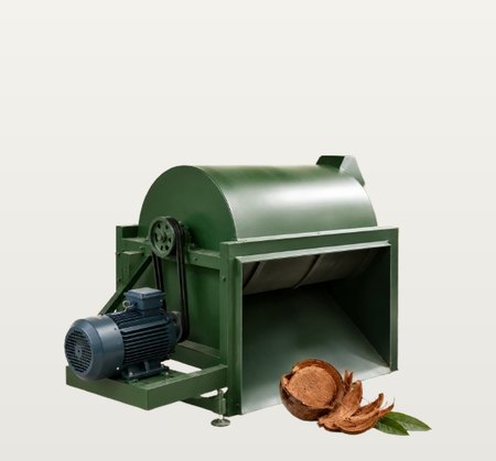A green drum shredder with a belt-driven electric motor and a wide inlet chute, beside a split coconut husk