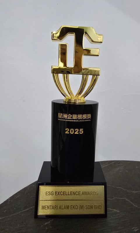 The 2025 Sin Chew Business Excellence Awards ESG Excellence Award trophy: a gold emblem on a black column, the plaque naming Mentari Alam Eko (M) Sdn Bhd