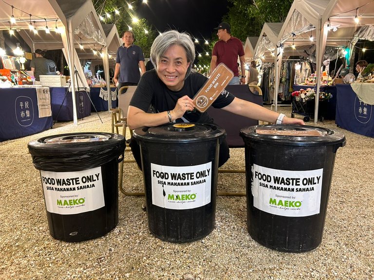 Chelsea Chee, founder of MAEKO, with three MAEKO food-waste bins at a night market.